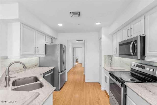 kitchen with white cabinetry, appliances with stainless steel finishes, sink, and light stone counters