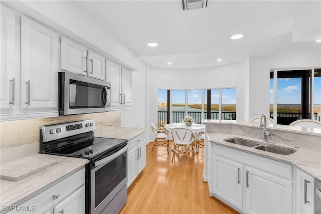 kitchen featuring sink, white cabinets, decorative backsplash, stainless steel appliances, and light stone countertops