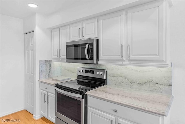 kitchen with white cabinetry, backsplash, light hardwood / wood-style floors, and appliances with stainless steel finishes