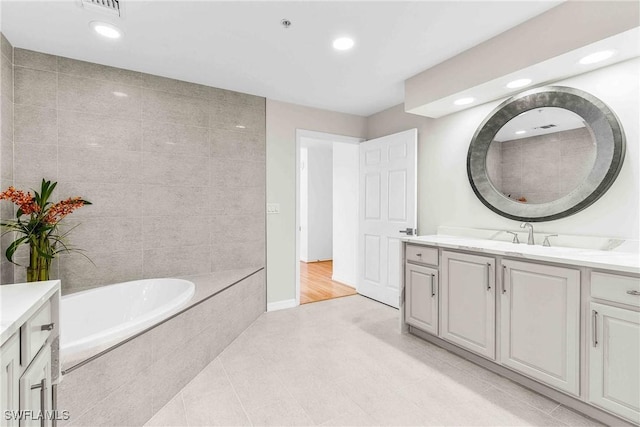 bathroom with vanity, tiled bath, and tile patterned flooring