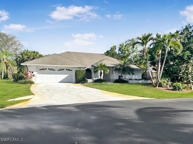 ranch-style house featuring a garage and a front lawn