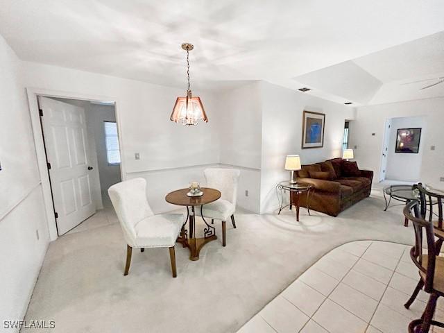 dining space with an inviting chandelier, light colored carpet, and a tray ceiling