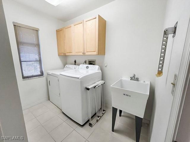 laundry area featuring separate washer and dryer, light tile patterned floors, sink, and cabinets