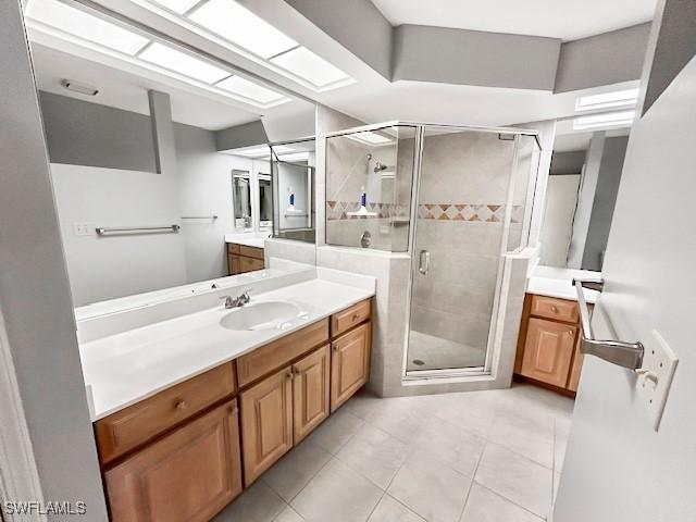 bathroom with an enclosed shower, vanity, a skylight, and tile patterned floors