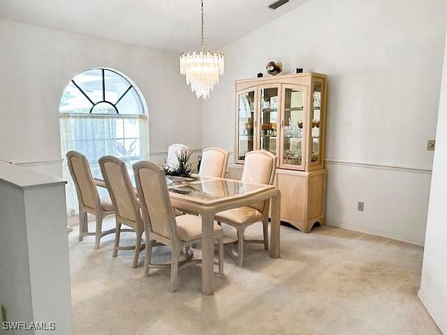 dining space with lofted ceiling, light carpet, and an inviting chandelier