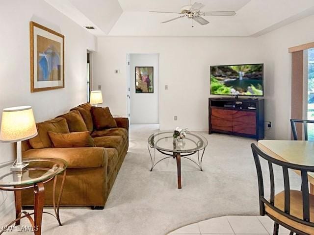 living room featuring light carpet, a raised ceiling, and ceiling fan