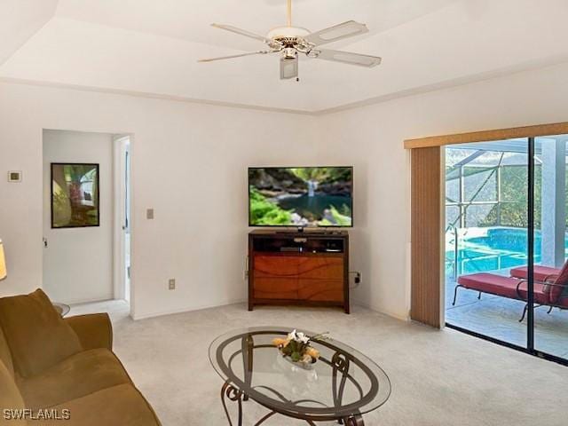 carpeted living room featuring ceiling fan and a raised ceiling