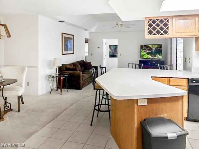 kitchen featuring light carpet, a breakfast bar area, a center island, and ceiling fan