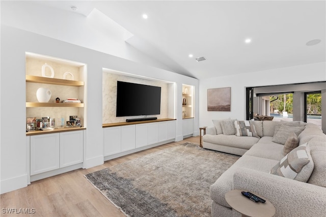 living room with lofted ceiling, built in features, and light hardwood / wood-style floors