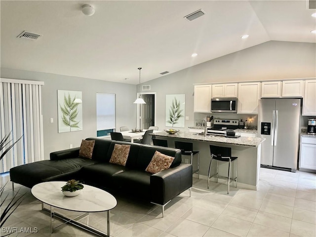 living room featuring visible vents, light tile patterned flooring, and vaulted ceiling