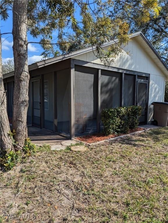 back of property with a sunroom and a lawn