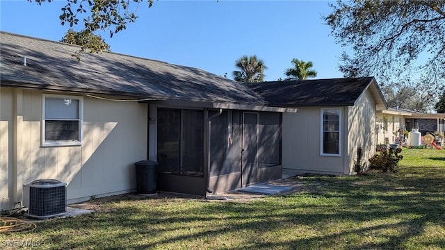 back of house featuring a sunroom, a yard, and central AC