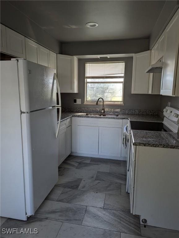 kitchen featuring white cabinetry, white appliances, dark stone counters, and sink