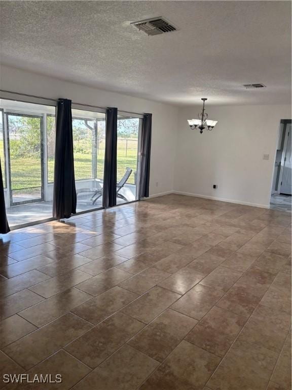 tiled spare room with a textured ceiling and a chandelier