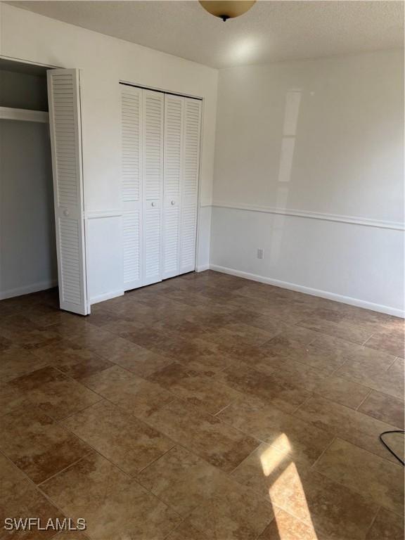 unfurnished bedroom with a textured ceiling and two closets