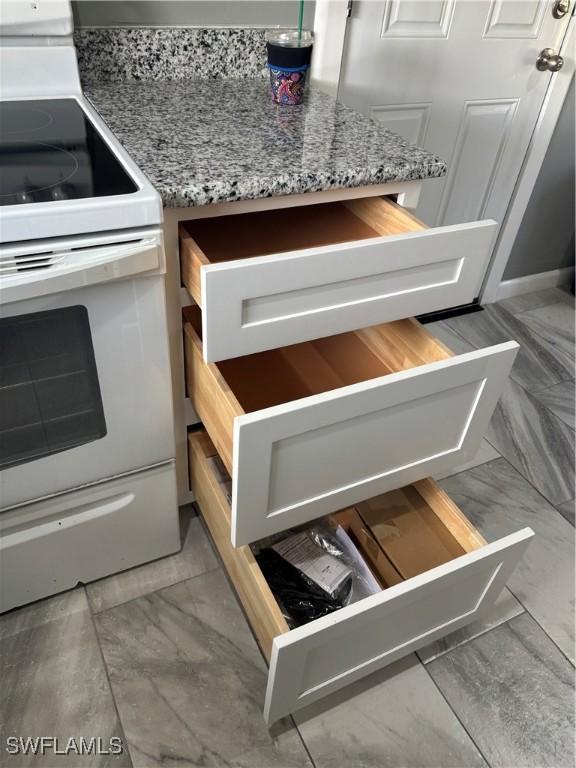 interior details with electric stove and light stone countertops