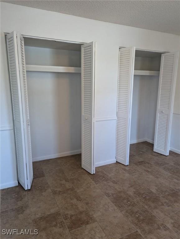 unfurnished bedroom featuring a textured ceiling and two closets