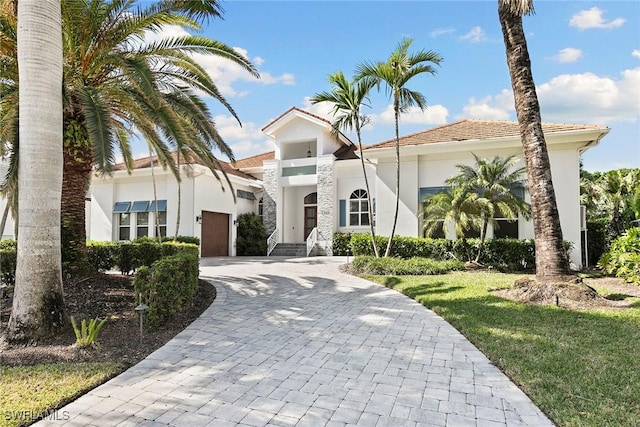 mediterranean / spanish home featuring a garage and a front lawn