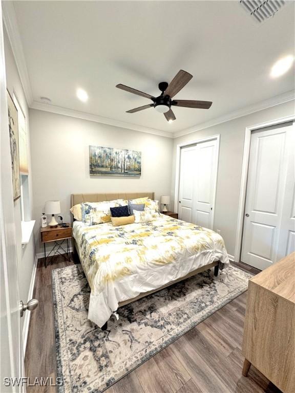 bedroom with dark wood-type flooring, ornamental molding, and ceiling fan