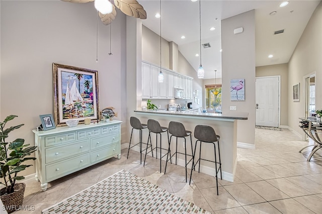 kitchen with high vaulted ceiling, kitchen peninsula, green cabinets, pendant lighting, and white cabinets