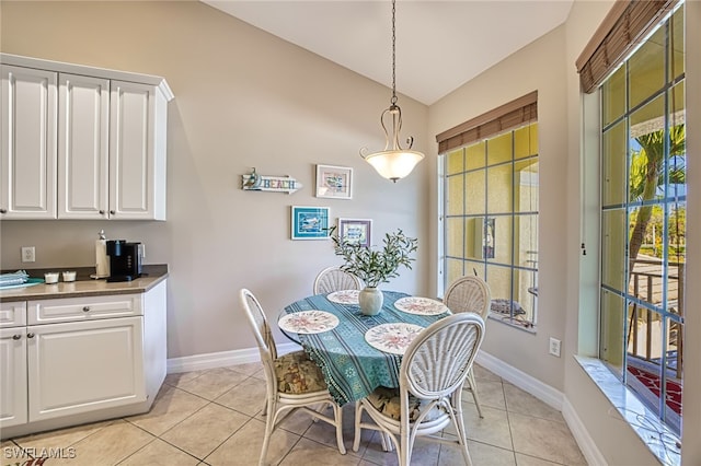 dining area with light tile patterned flooring and vaulted ceiling