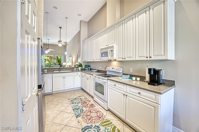 kitchen with sink, light tile patterned floors, white cabinets, and white appliances