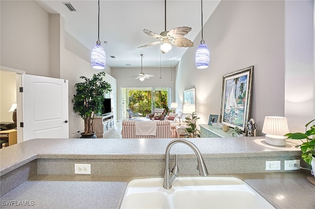 kitchen featuring decorative light fixtures, sink, ceiling fan, and a towering ceiling