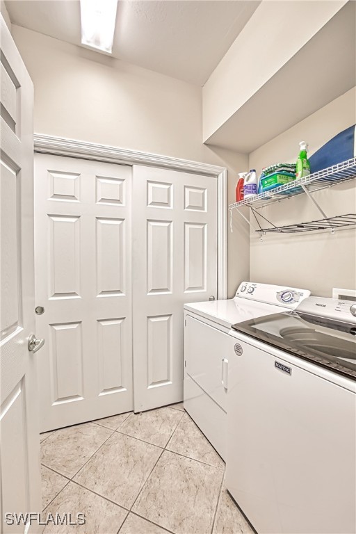 laundry area featuring washing machine and clothes dryer and light tile patterned floors