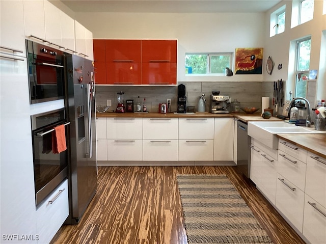 kitchen featuring sink, white cabinetry, backsplash, stainless steel appliances, and dark hardwood / wood-style flooring