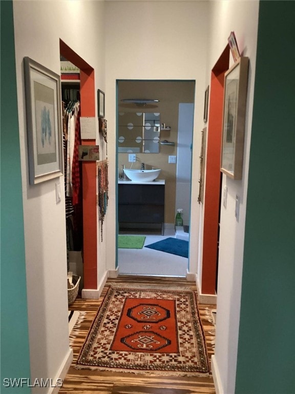 corridor with sink and hardwood / wood-style floors