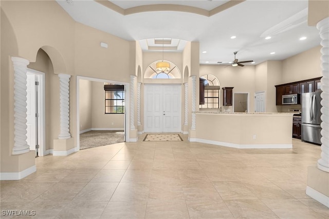 tiled entryway with a high ceiling, ornate columns, and ceiling fan