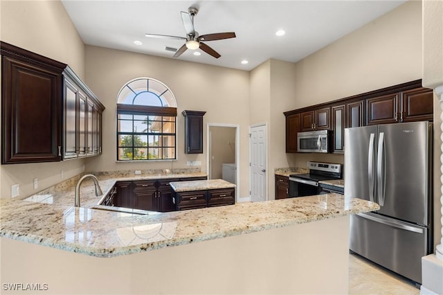 kitchen featuring dark brown cabinets, stainless steel appliances, light stone countertops, ceiling fan, and kitchen peninsula