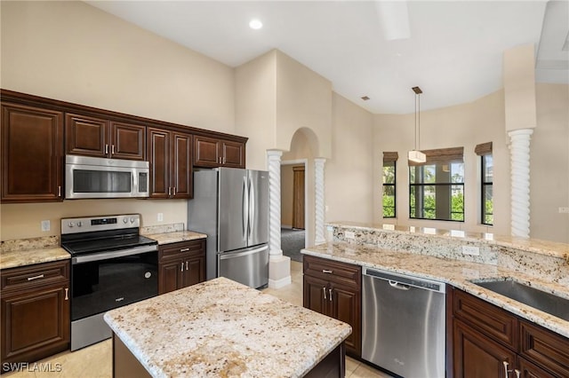 kitchen with appliances with stainless steel finishes, dark brown cabinetry, light stone countertops, decorative light fixtures, and ornate columns