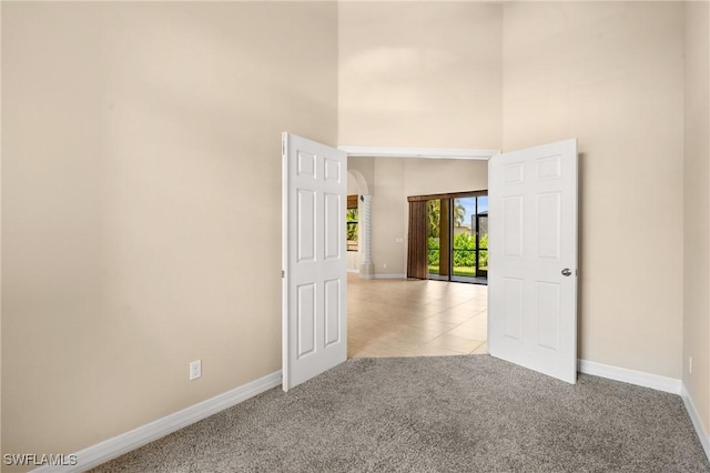 empty room featuring a high ceiling and light carpet