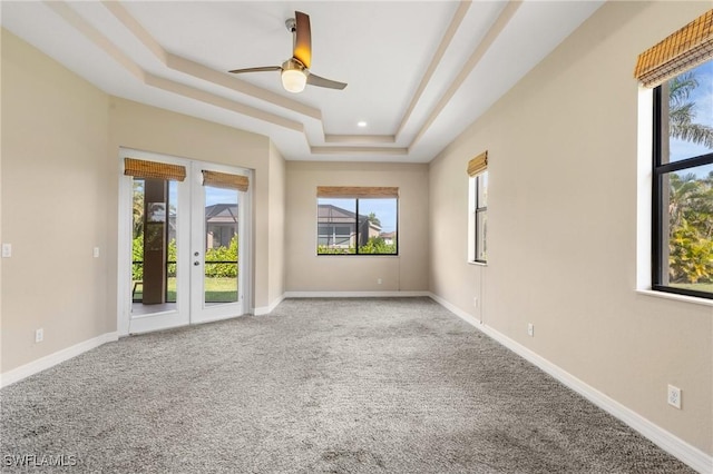 carpeted spare room featuring french doors, ceiling fan, and a raised ceiling