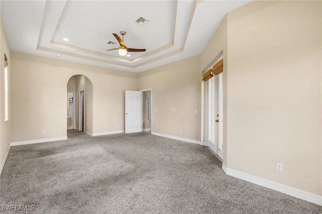 carpeted empty room with a raised ceiling and ceiling fan