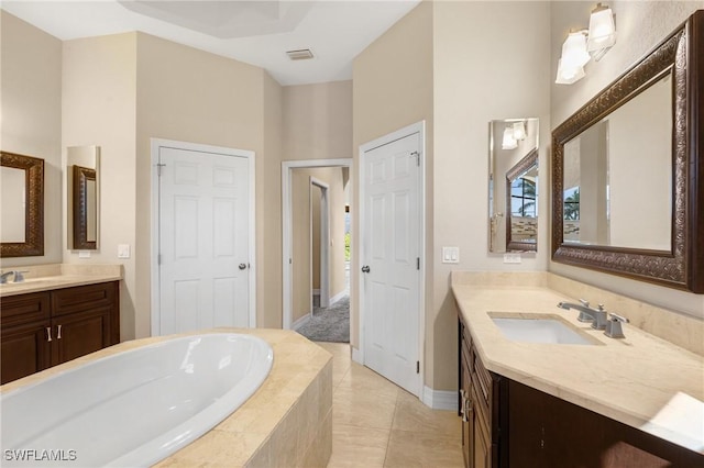 bathroom with tiled bath, tile patterned flooring, and vanity