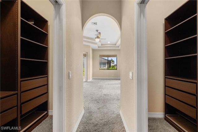 hall featuring a raised ceiling and light colored carpet