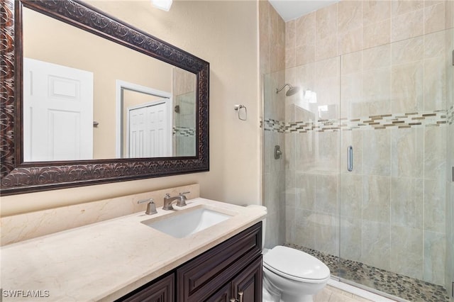 bathroom featuring toilet, vanity, and a shower with door