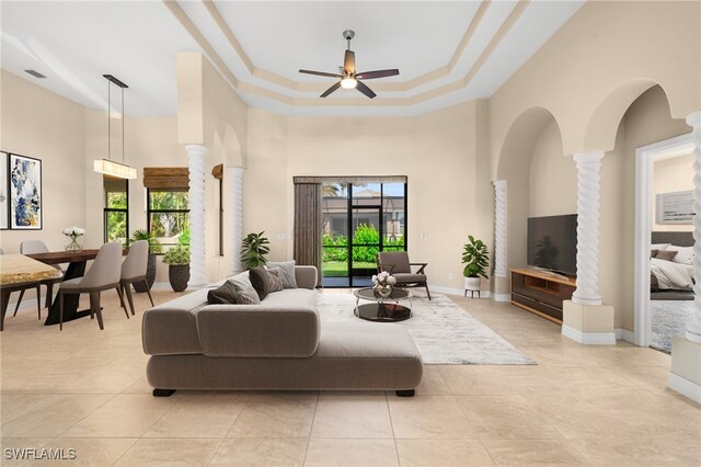 living room featuring ceiling fan, ornate columns, a towering ceiling, and a wealth of natural light