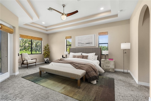 bedroom featuring ceiling fan, a raised ceiling, and carpet