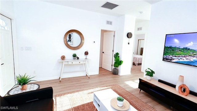 living area with visible vents, lofted ceiling, and wood finished floors