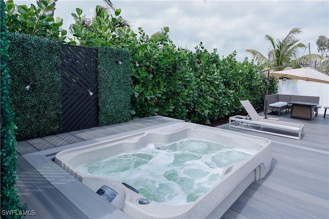 exterior space featuring a wooden deck, fence, and hot tub deck surround