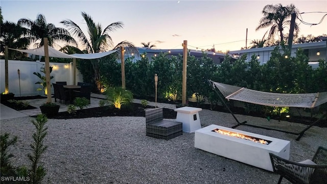 patio terrace at dusk featuring fence and an outdoor fire pit