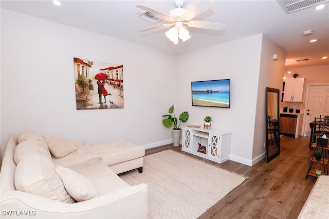 living area with light wood-style floors, visible vents, baseboards, and a ceiling fan