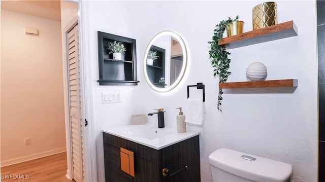 bathroom featuring vanity, toilet, wood finished floors, and baseboards