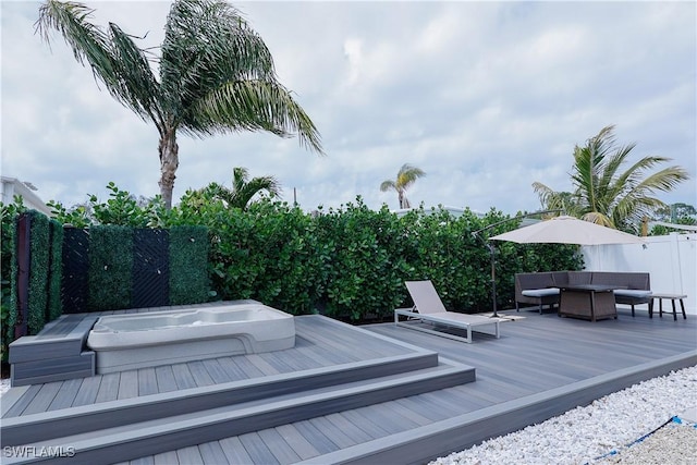 deck featuring an outdoor living space, a fenced backyard, and hot tub deck surround