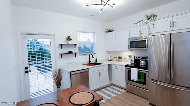 kitchen with a sink, a wealth of natural light, appliances with stainless steel finishes, and light wood-style floors