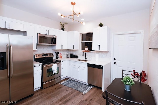 kitchen with white cabinetry, a chandelier, a sink, stainless steel appliances, and decorative backsplash