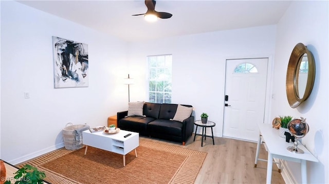 living room featuring ceiling fan, light wood-style floors, and baseboards